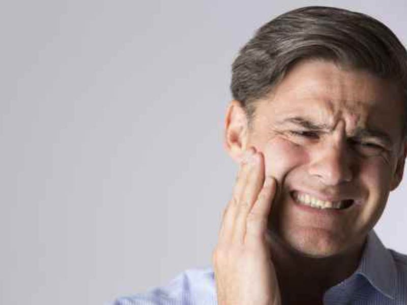 Man with a toothache hurting tooth with a hand to his cheek